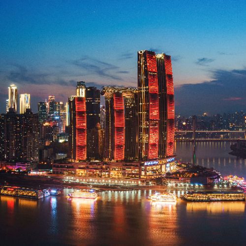 Esta toma ofrece una perspectiva horizontal y un poco más cercana del frente costero urbano de Chongqing, centrándose en el contraste entre lo tradicional y lo moderno.